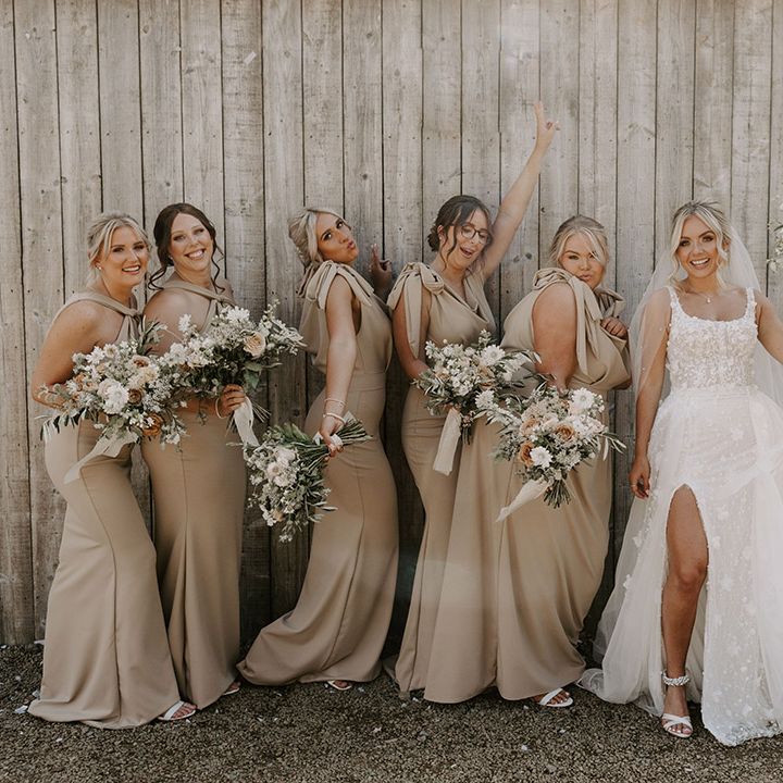 Bridesmaids in neutral light brown bridesmaid dresses posing with the bride in a Eleganza Sposa wedding dress for Hidden River Cabins wedding 