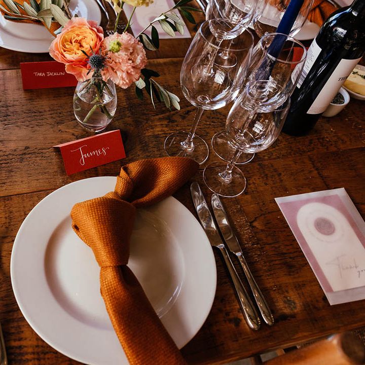 White wedding plate with copper orange napkin and place name with wedding favours in frosted envelopes 