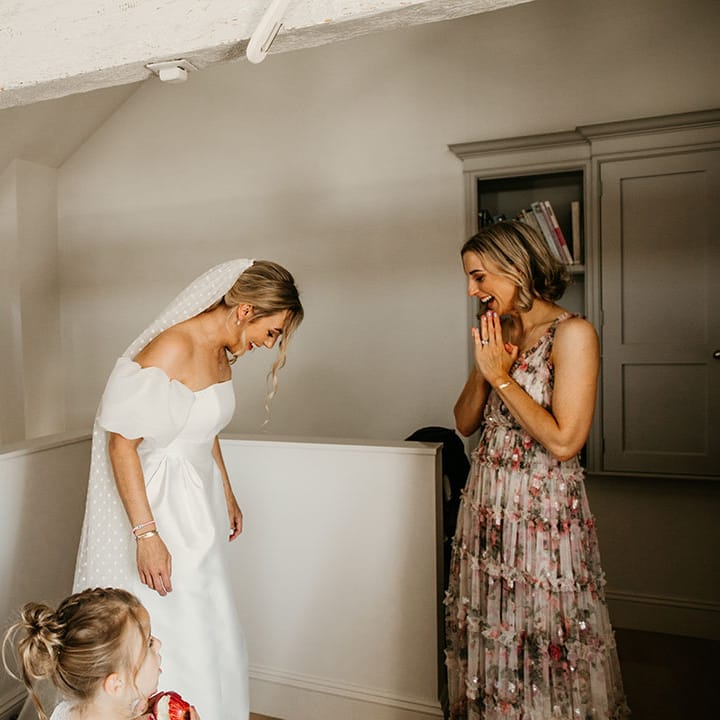 Bridesmaids in mismatched bridesmaid dresses help the bride with the finishing touches as she gets ready for the day 