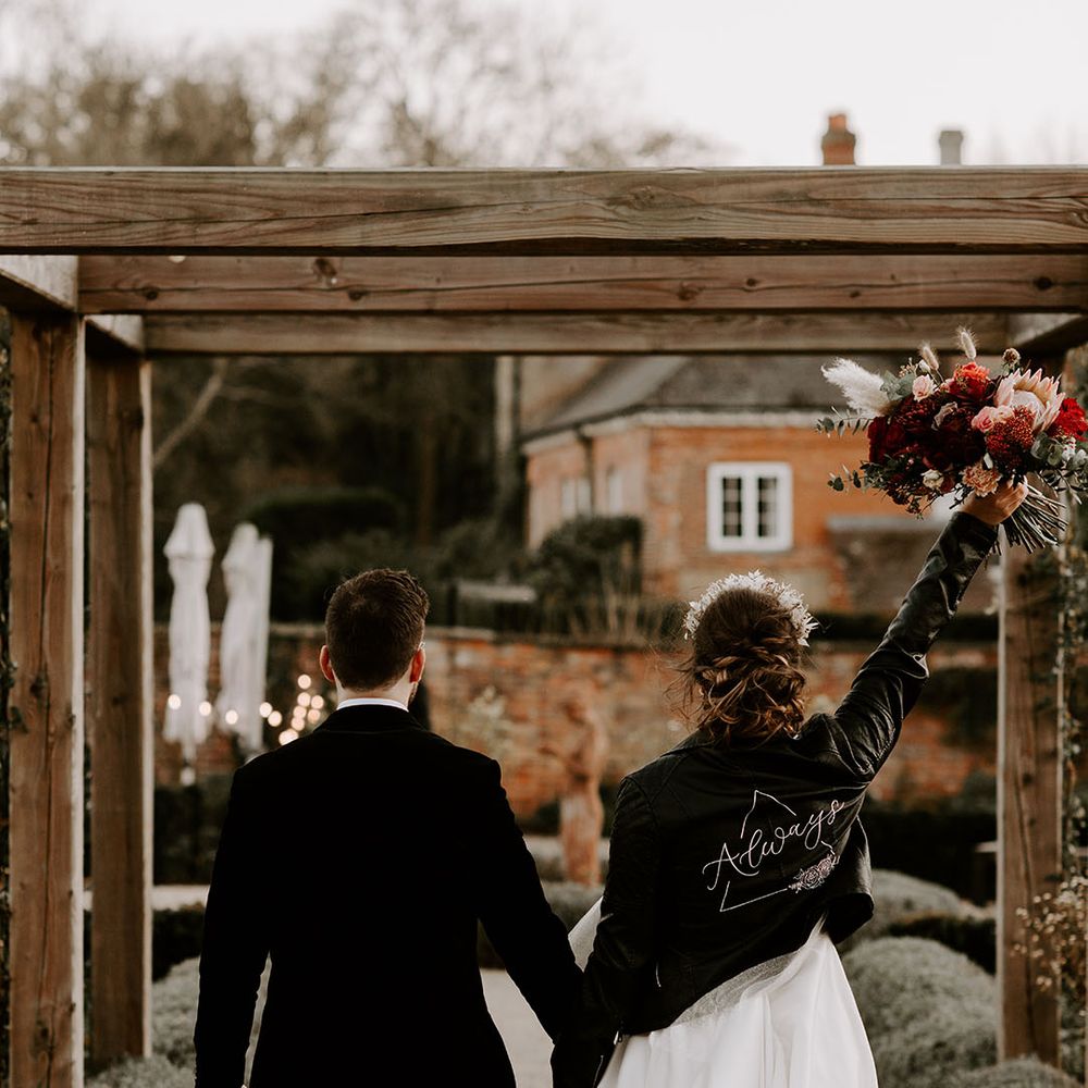 Bride wearing leather jacket walking along with the groom at Syrencot wedding venue 
