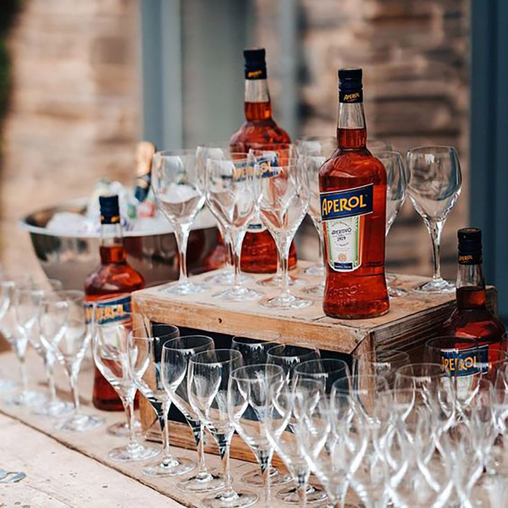 Aperol spritz drinks station with bottles of Aperol and empty glasses by James Fear Photography