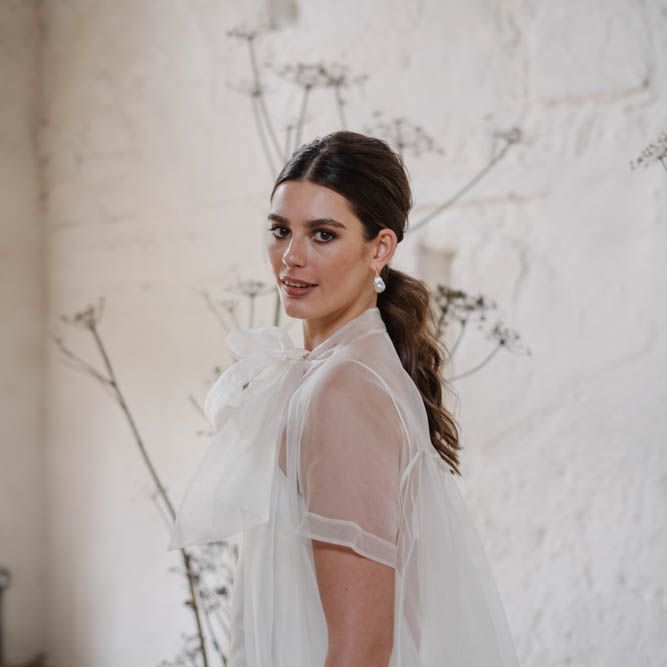 Bride with ponytail wearing a sheer blouse 