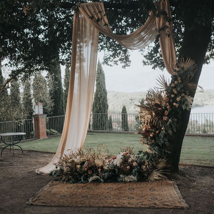 Altar styled by In Tuscany Wedding with rugs, drapes and floral arrangements 