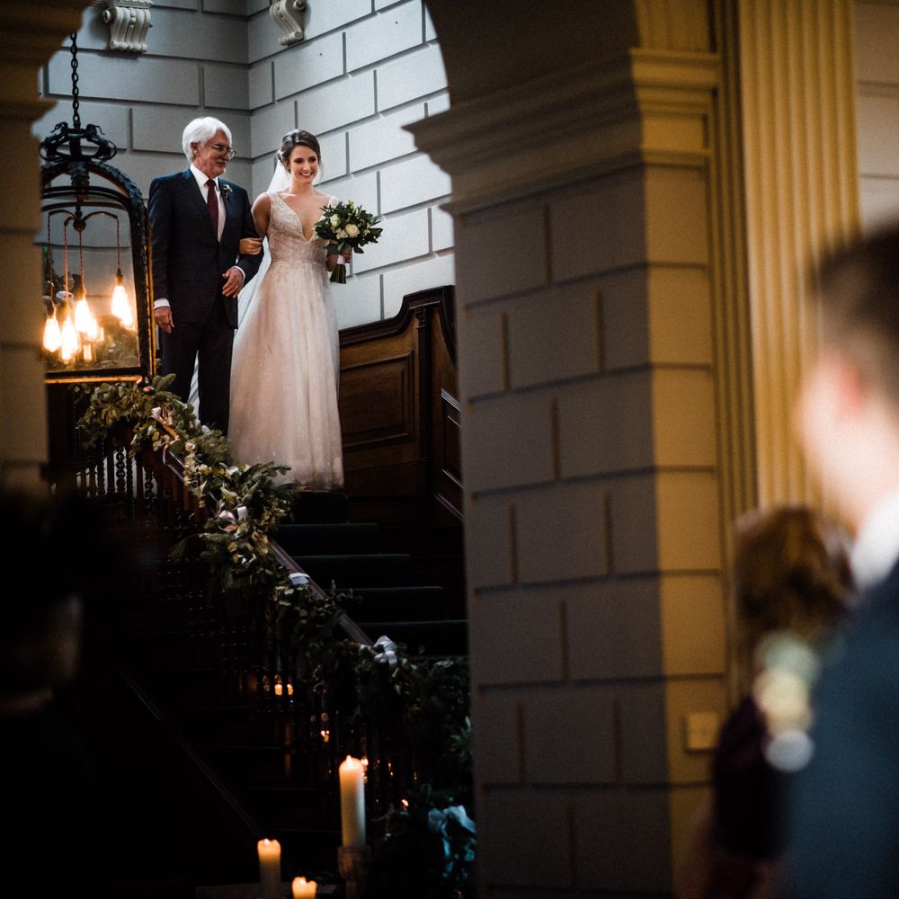 Bride walks down the stairs during ceremony for groom to see her for the first time
