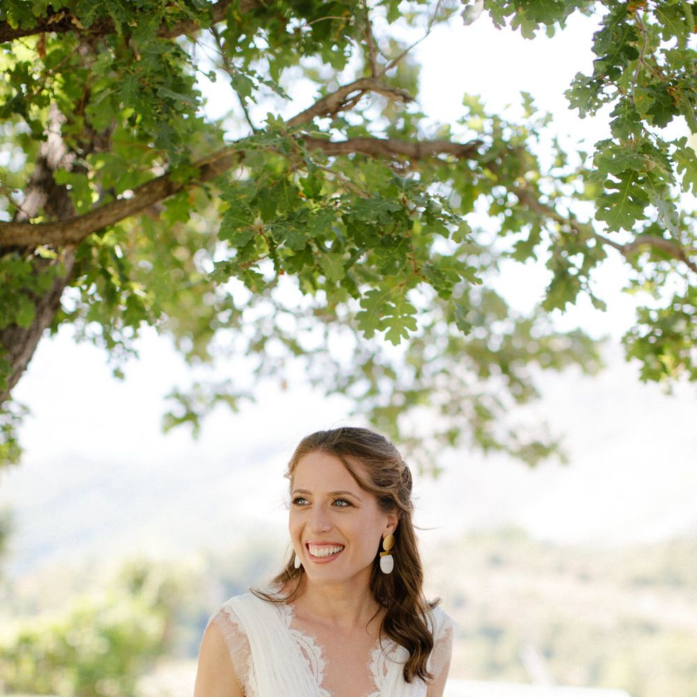 The bride standing under a tree in the Greek countryside