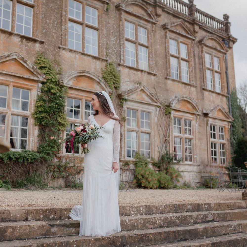 Bride outside Brympton House wearing beaded long sleeve wedding gown
