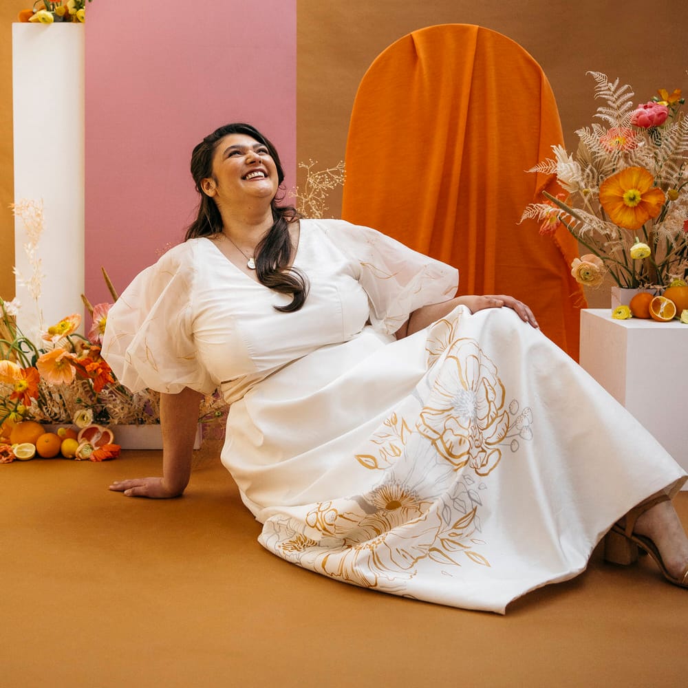Bride sitting on the floor and laughing in her wedding separates by Paper To Lace
