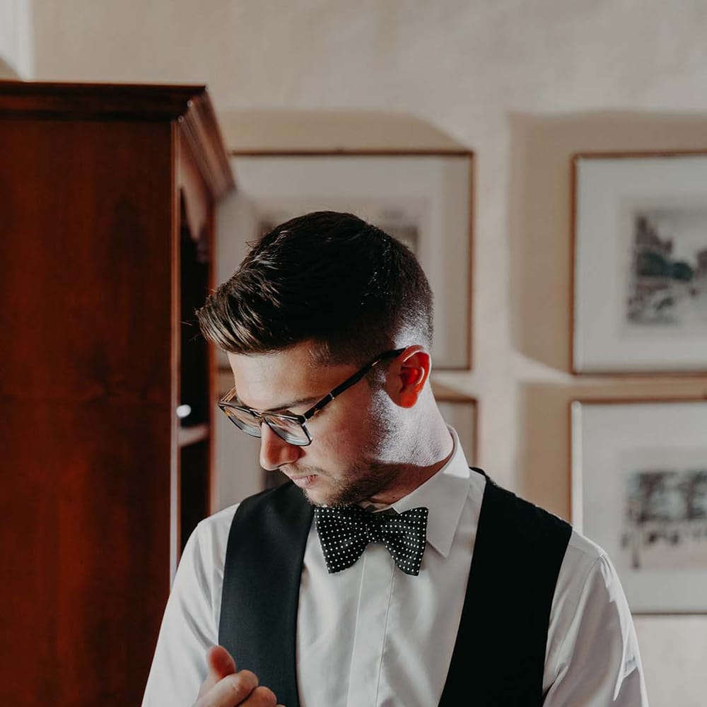 Groom does up his cufflink on the day of his wedding whilst wearing black tie | Royal Studio