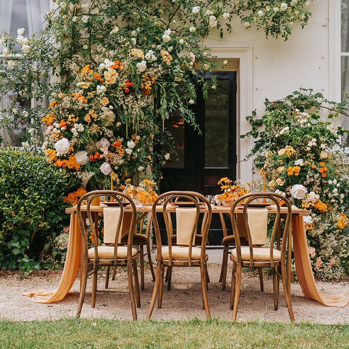 Outdoor wedding reception at Modern Hall, London with wooden chairs, orange flowers and table decor 