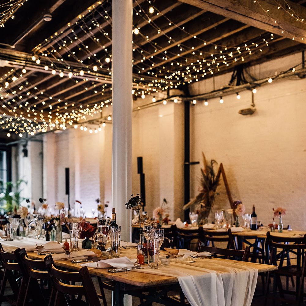100 Barrington wedding reception with fairy lights, chiffon table runner and flower stems in bottles 