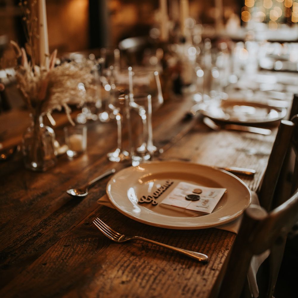 Rustic wedding table setting with dried florals, wooden table and fairy lights for barn wedding reception