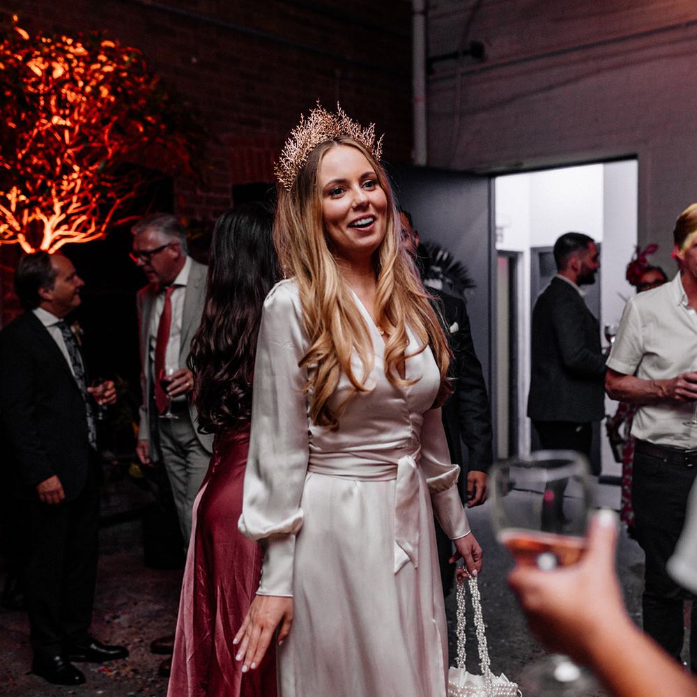 Stylish bride n a satin wrap evening dress with pearl handbag and gold crown bridal accessories 
