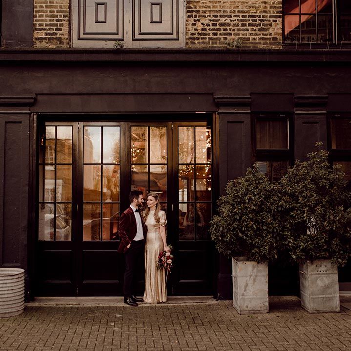 Bride and groom stand together in London city near their industrial wedding venue