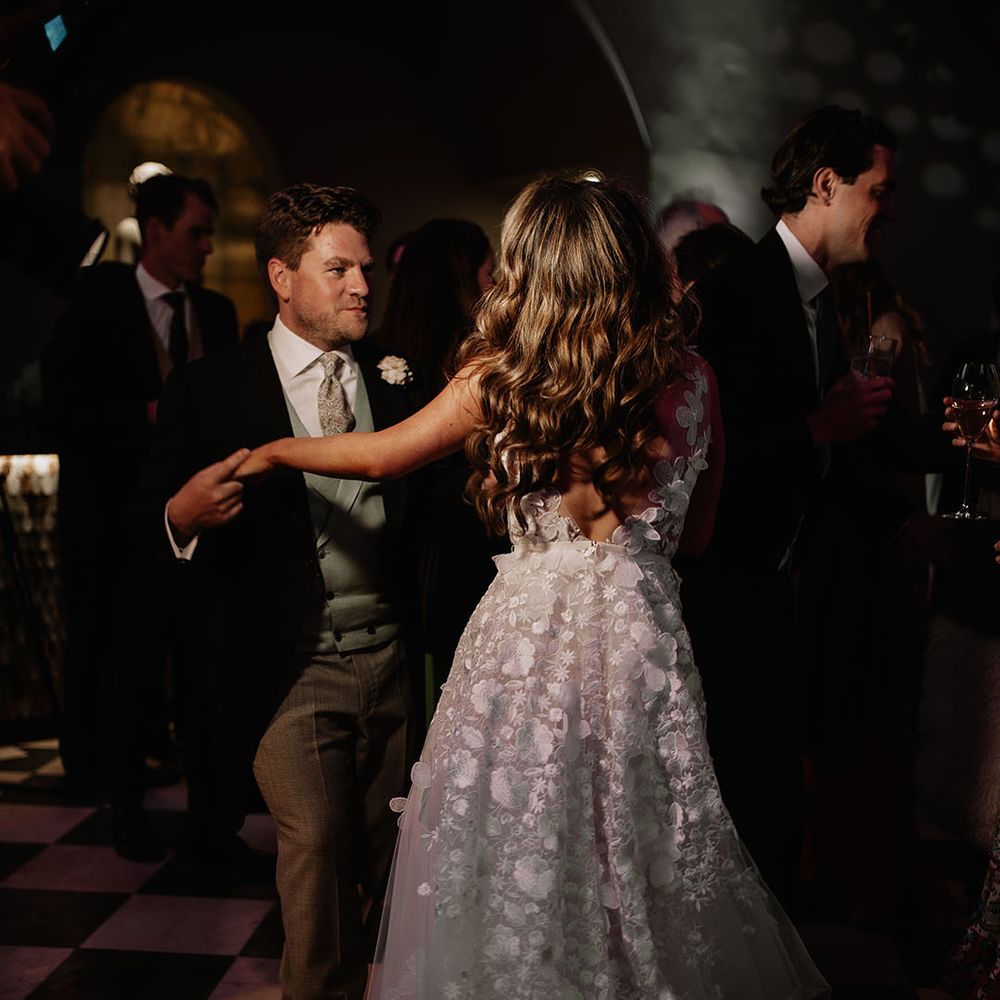 Bride and groom dance together on the dance floor with bride in flower applique wedding dress and groom in morning suit 