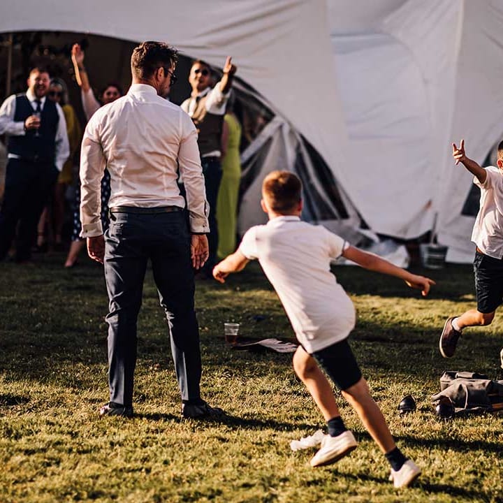 Wedding guests and children play a game of football before the wedding breakfast 