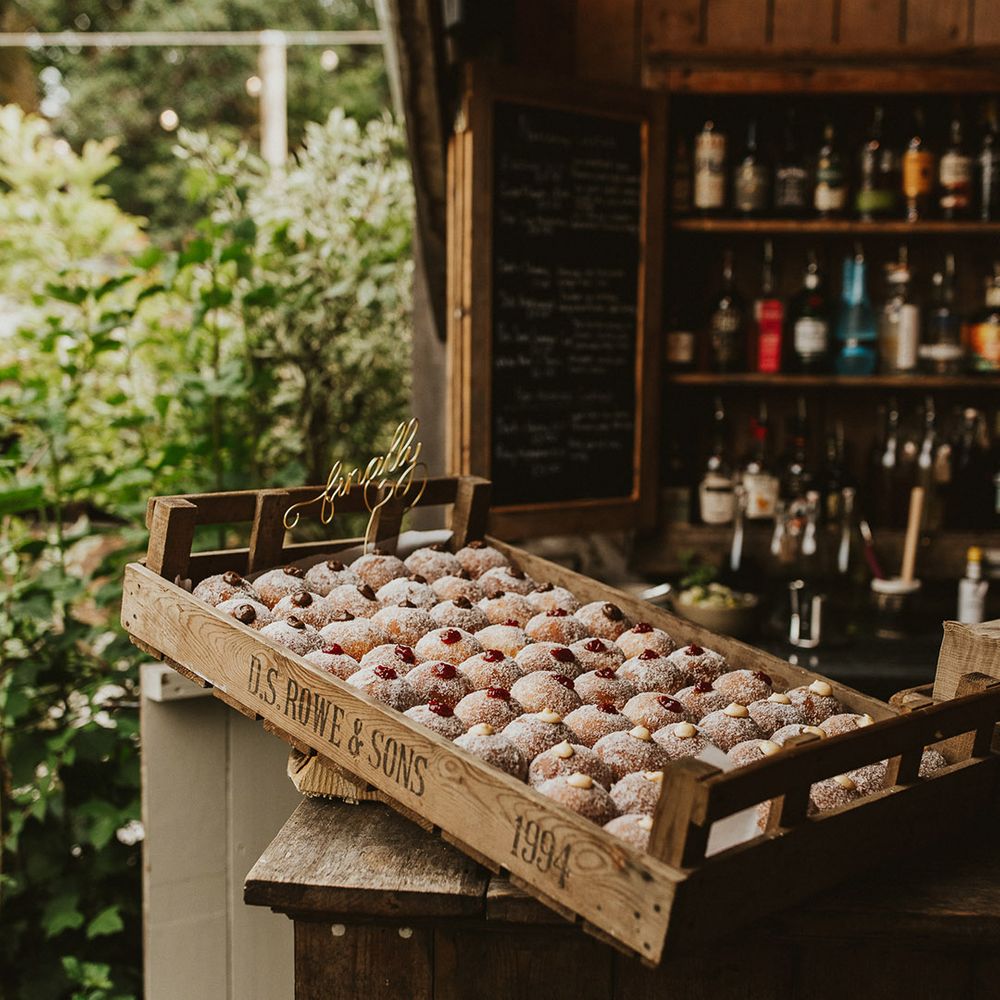 Filled doughnuts wedding favours in a wooden crate on the bar 