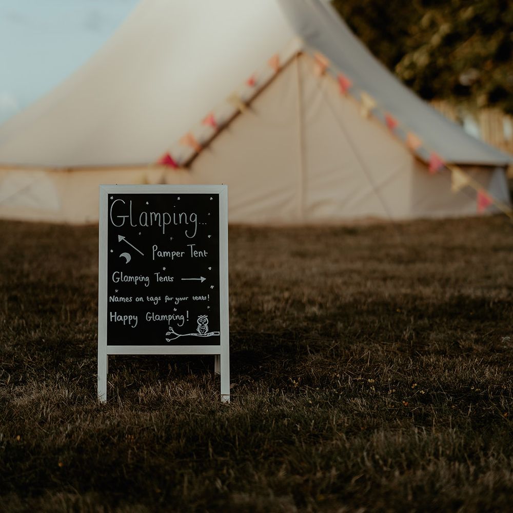 Glamping tents for festival style wedding with a chalk board sign directing the wedding guests 