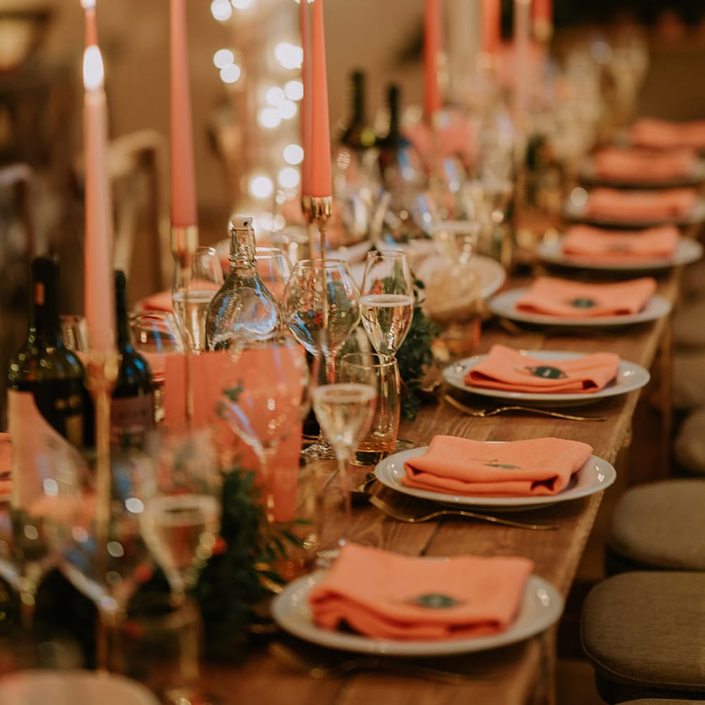 Reception room of Marylebone Town Hall with silver and gold wedding streamers, orange tapered candles, orange napkins, orange rose and foliage tablerunners and fairy lights 