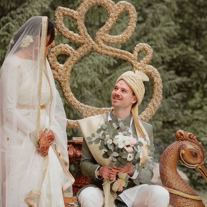 Groom in a green Sherwani holding a bouquet under a mandal with his South Asian bride in a cream lehenga 