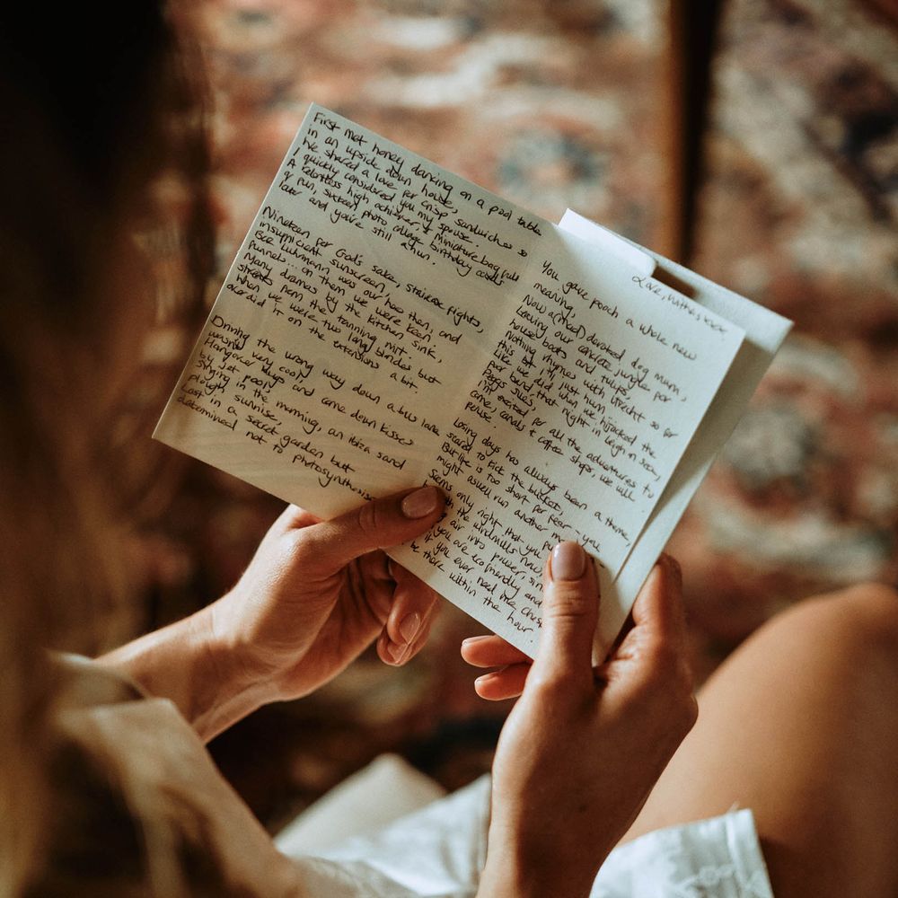 Bride reading letter from groom on the morning of the wedding whilst in bridal pyjamas