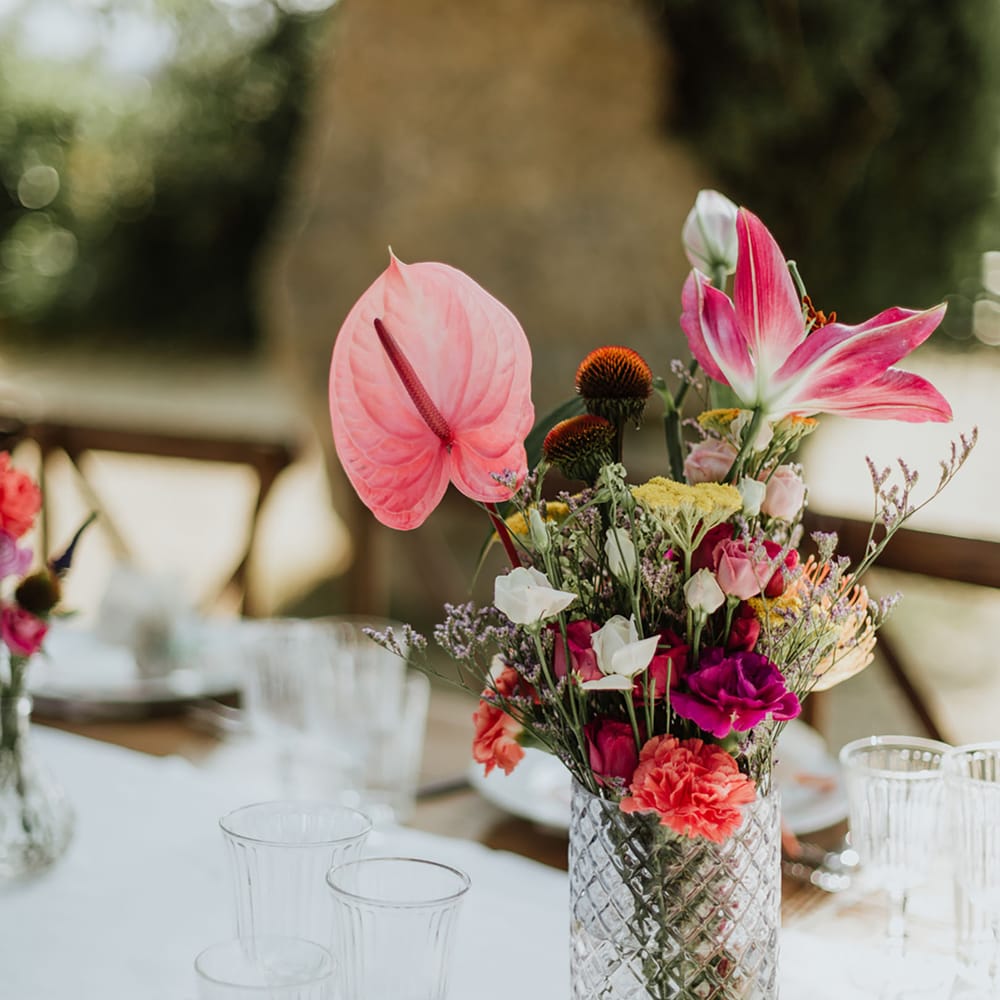 floral centrepiece cosisting of pink Anthurium, Oriental Lillies, coral Carnations, magenta Peonies and wildflower in a crystal vase