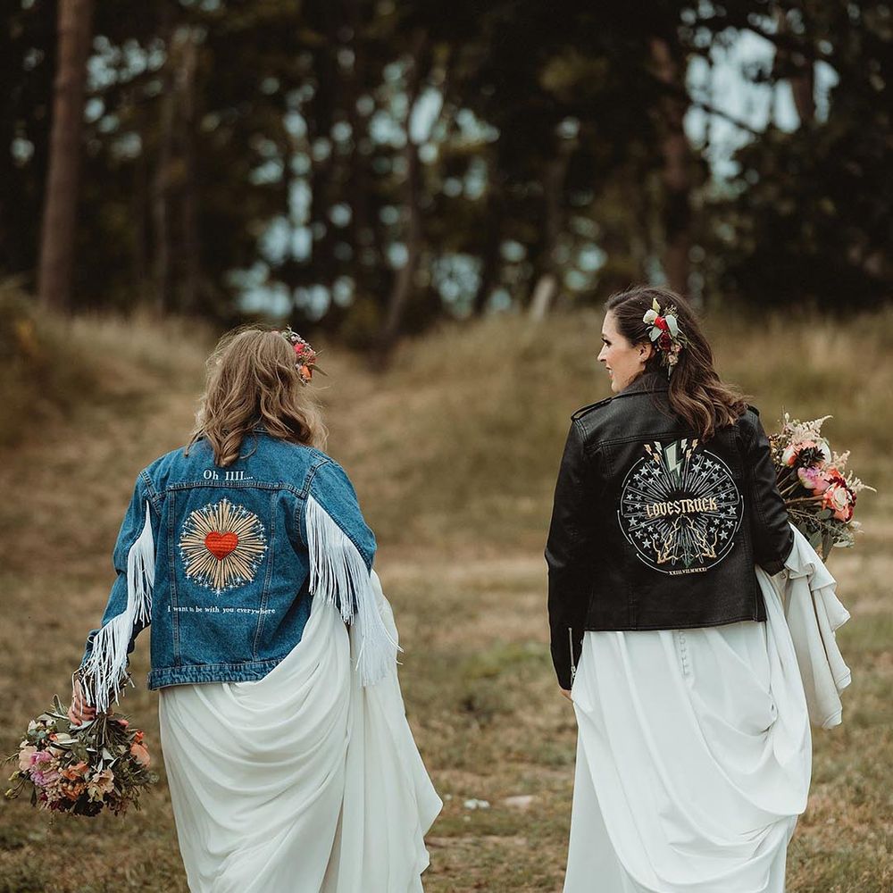 Lesbian wedding with the bride in a denim jacket with a custom motif based on her favourite song with bride in leather jacket with similar motif design