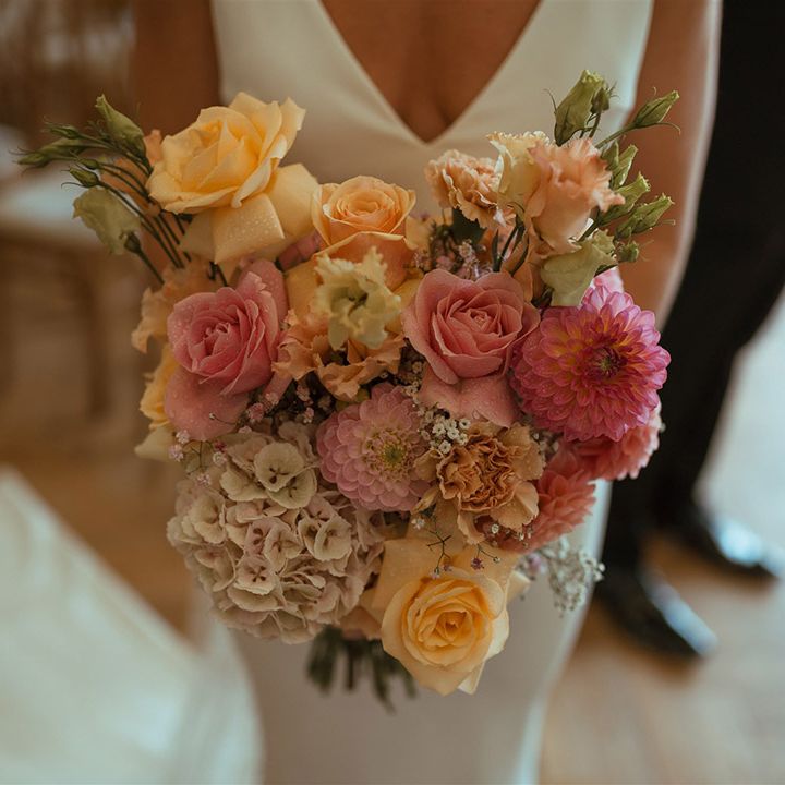 Bride holding pink and orange roses with gypsophila bouquet 