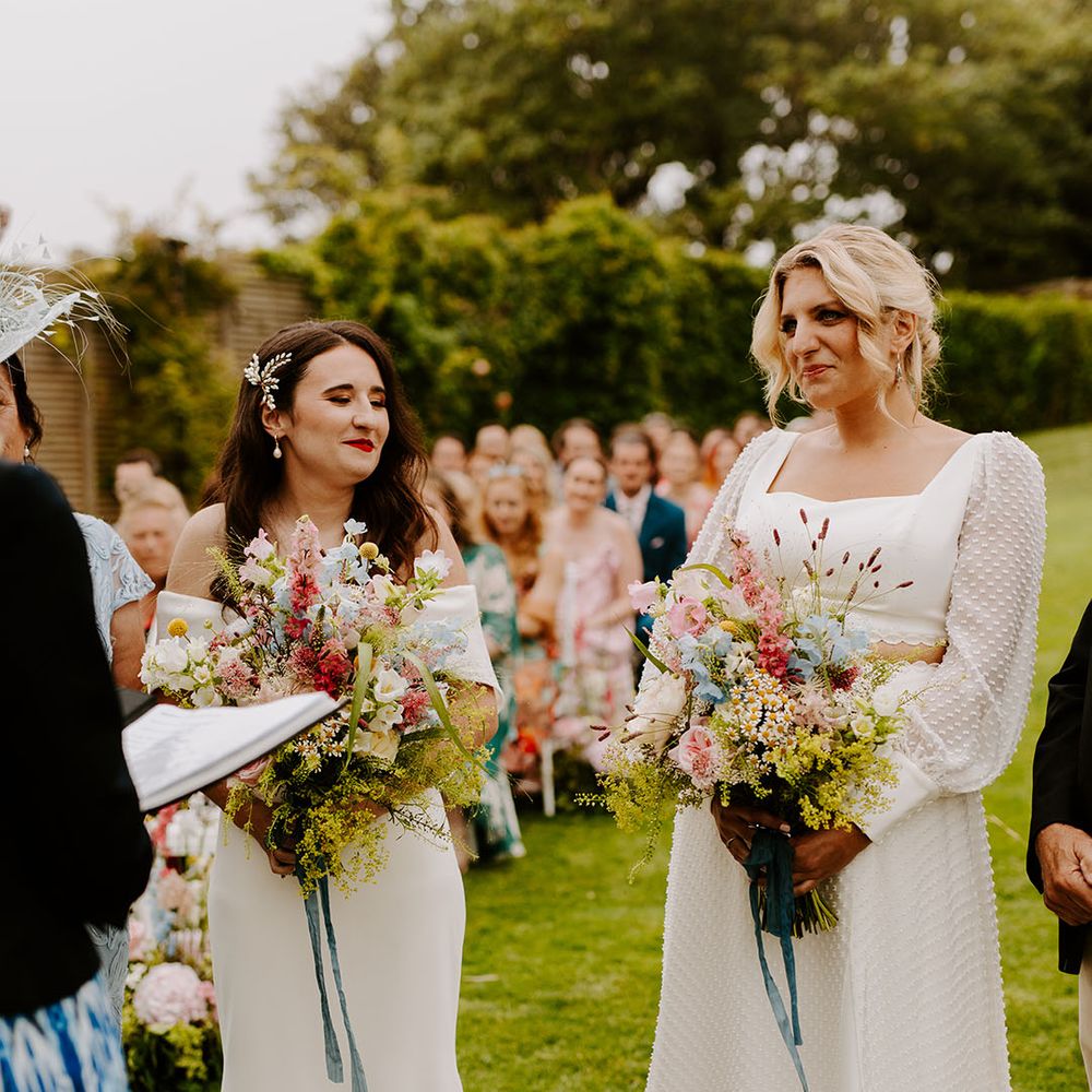 Bride wearing a spotted long sleeve bridal two piece with another bride in off the shoulder wedding dress for lesbian wedding 