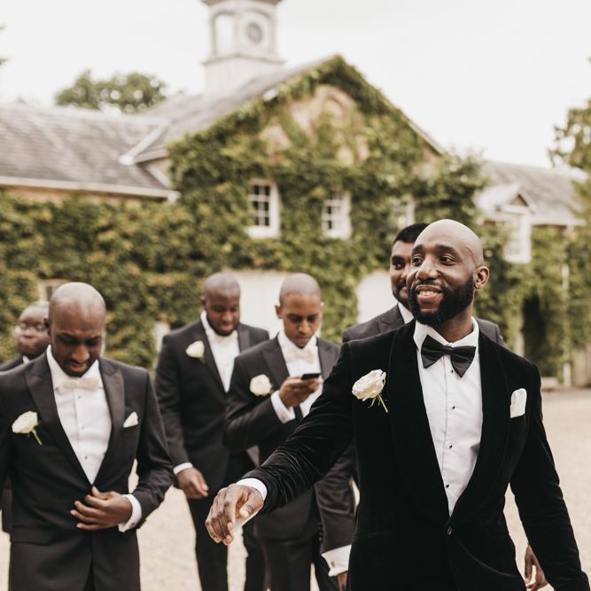 Black groom in a black velvet tuxedo jacket with his groomsmen 