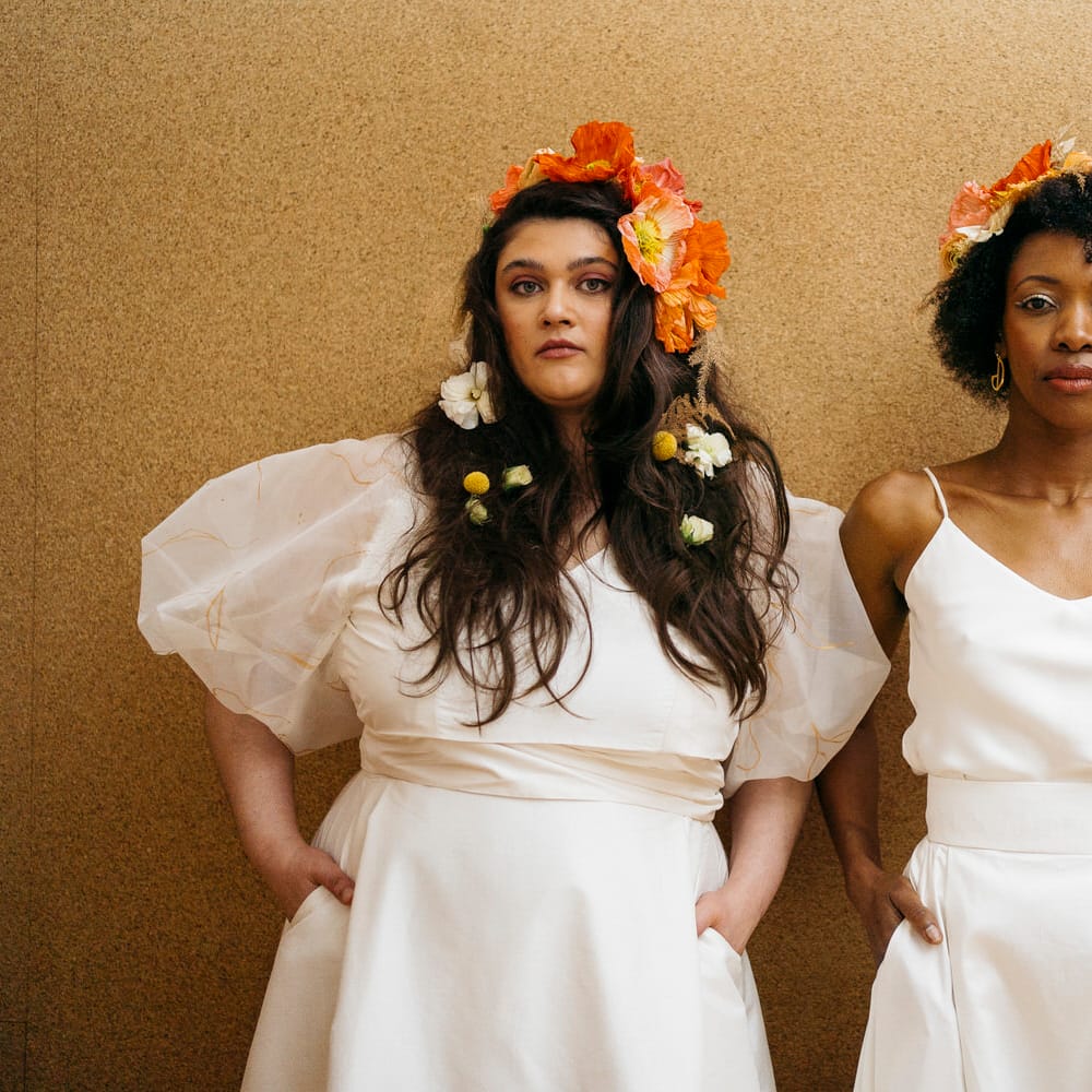 Brides with fresh flower hair accessories, wearing puff sleeve and spaghetti strap bridal separates from Paper To Lace