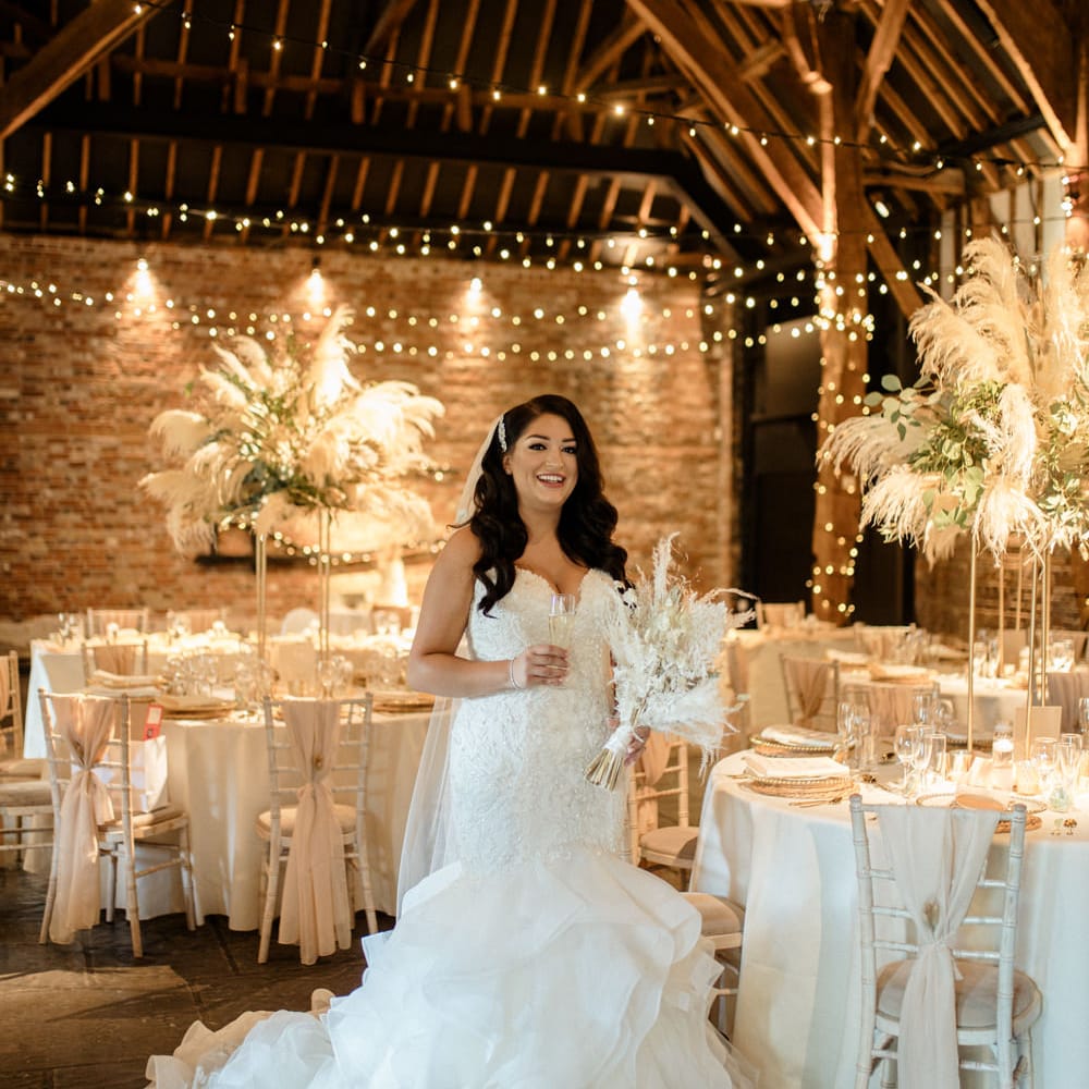 Bride in a strapless lace wedding dress with fishtail skirt standing in the wedding reception at Cooling Castle Barn 
