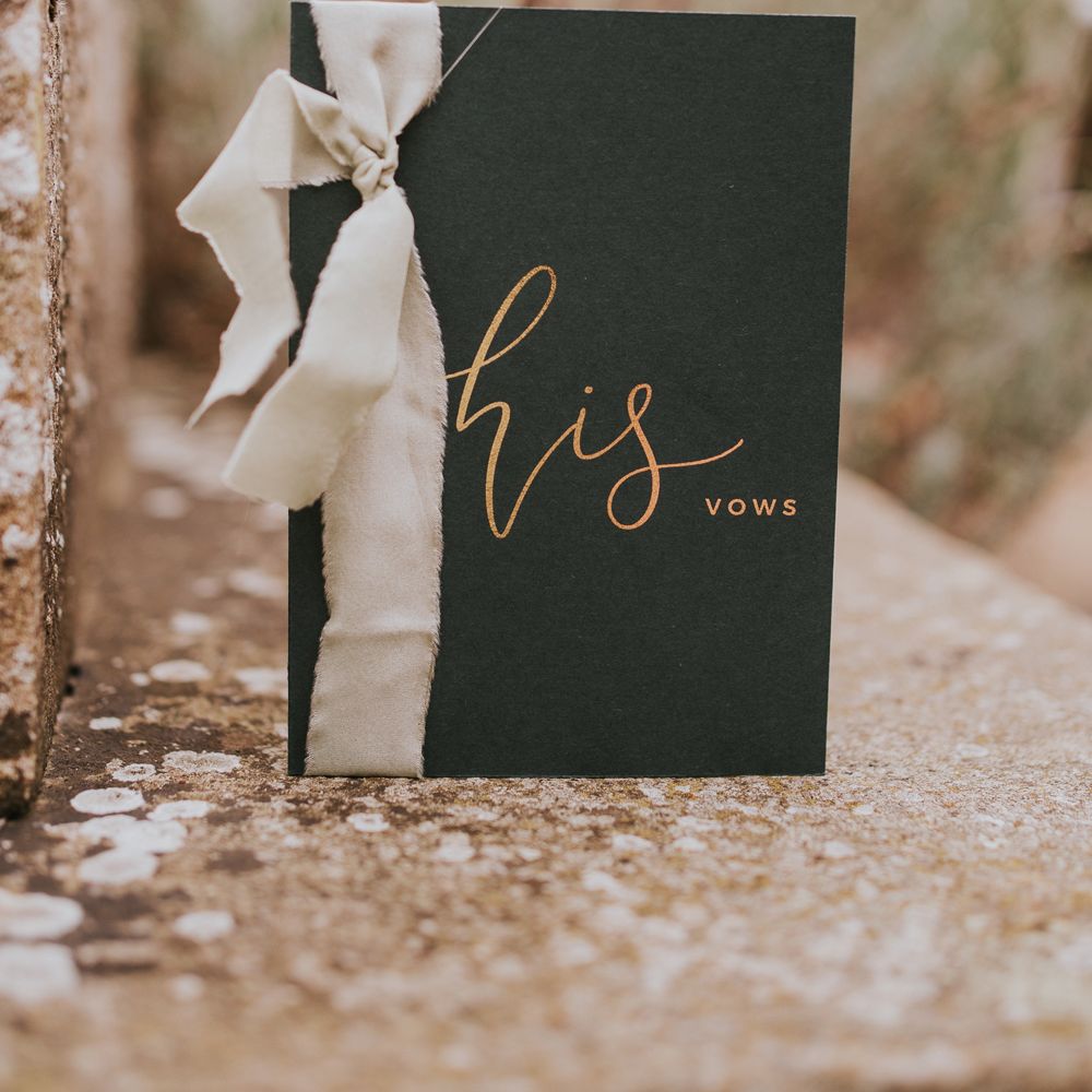 Dark green vow booklet with gold calligraphy and white ribbon for outdoor wedding ceremony
