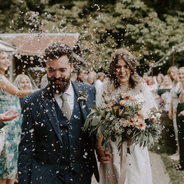 Bride wears E&W Couture wedding gown whilst holding floral bouquet 
