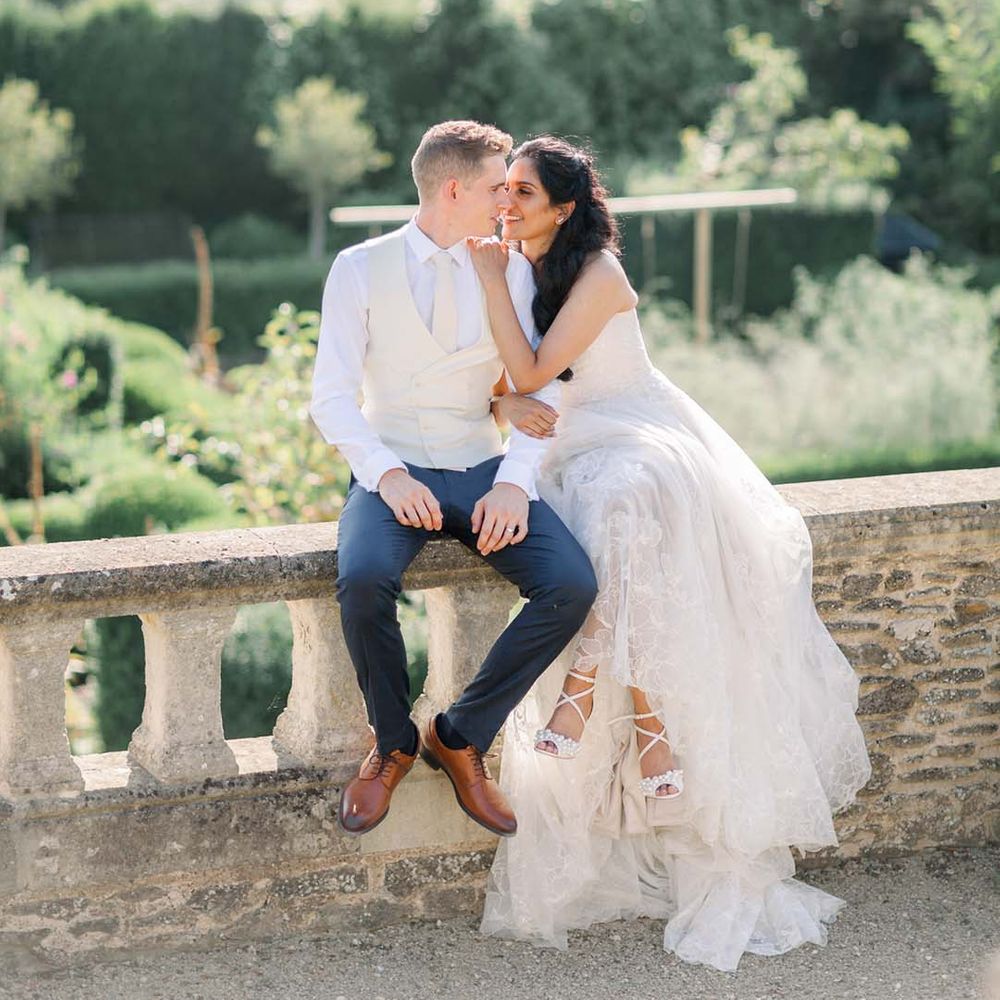 Bride & groom kiss outdoors in front of gardens on their wedding day
