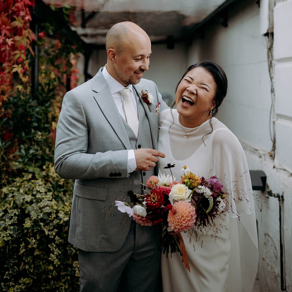Bride & groom laugh with one another on their wedding day outdoors 