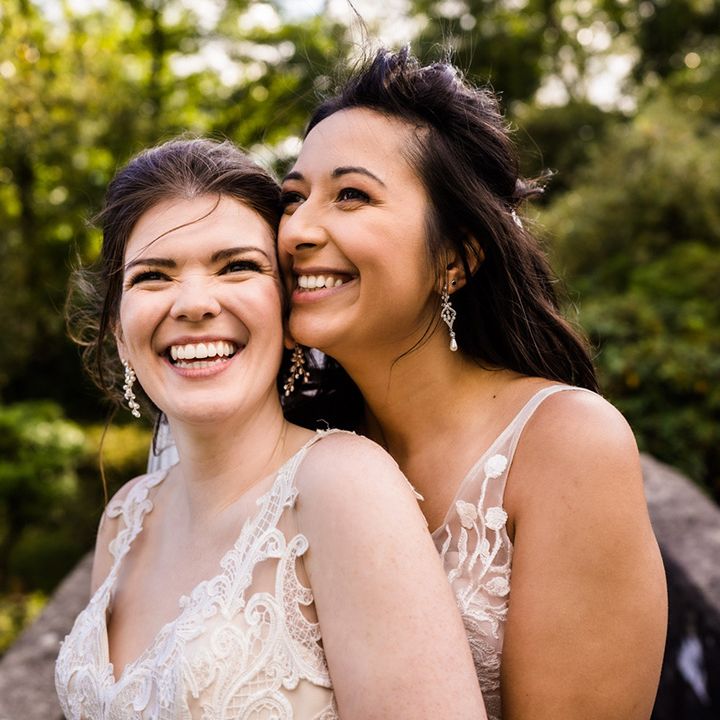 Smiling brides stand together on their wedding day at Foxtail Barns wedding venue