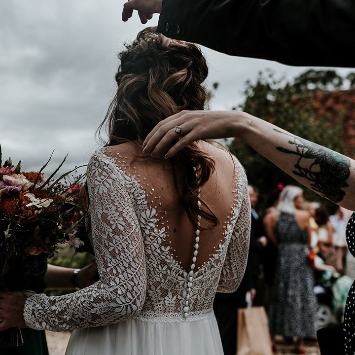 Bride in illusion lace back wedding dress with button detail and long sleeves