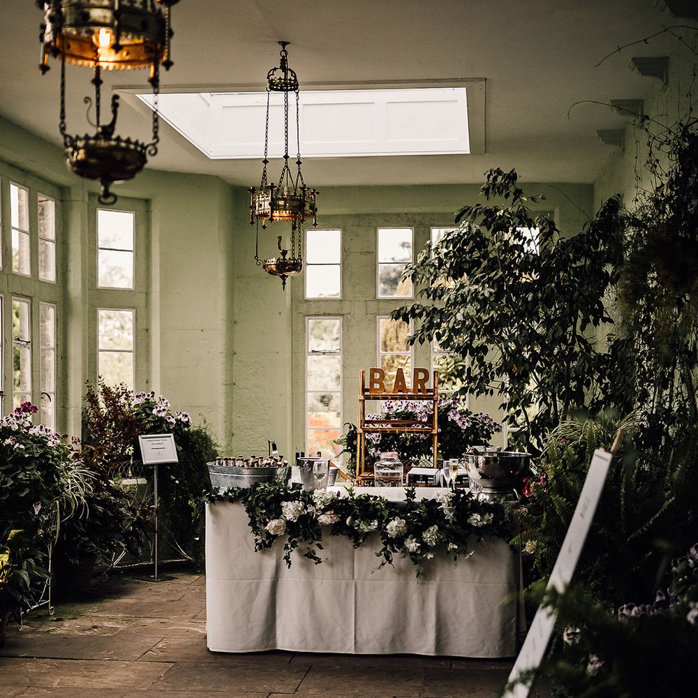 Bar area at Wadhurst Castle in green room with lots of foliage and buckets of drinks and ice 