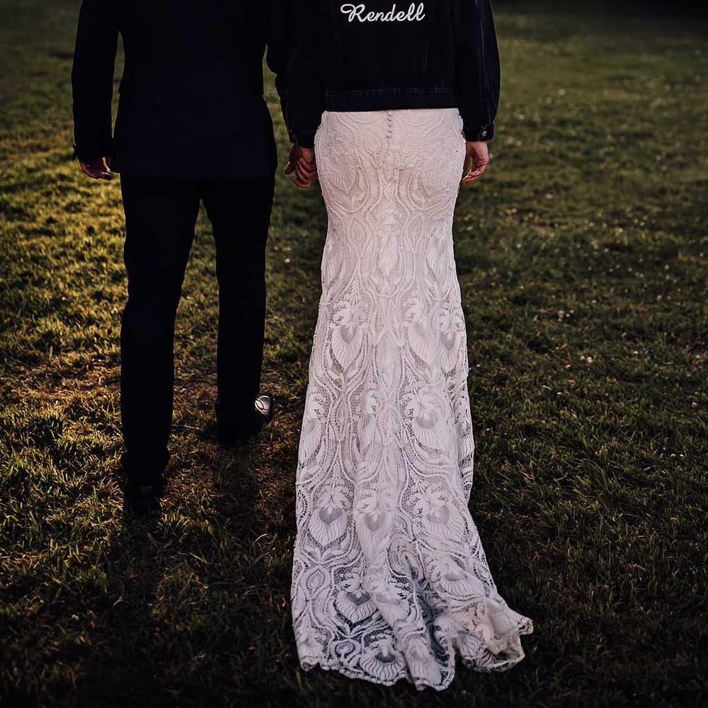 Bride in black denim jacket with embroidered personalised detail with groom in blue tuxedo