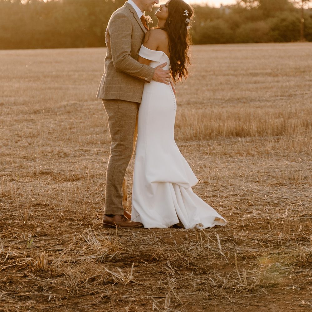 Bride and groom look into each other's eyes as they pose for a golden hour shot 