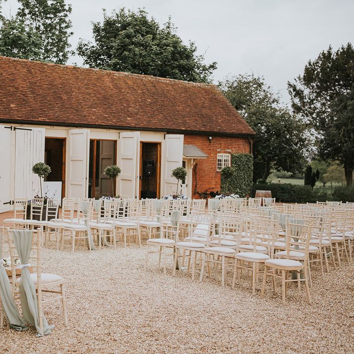Outdoor wedding ceremony set up with sage green fabric chair back decor with copper frame altar decor