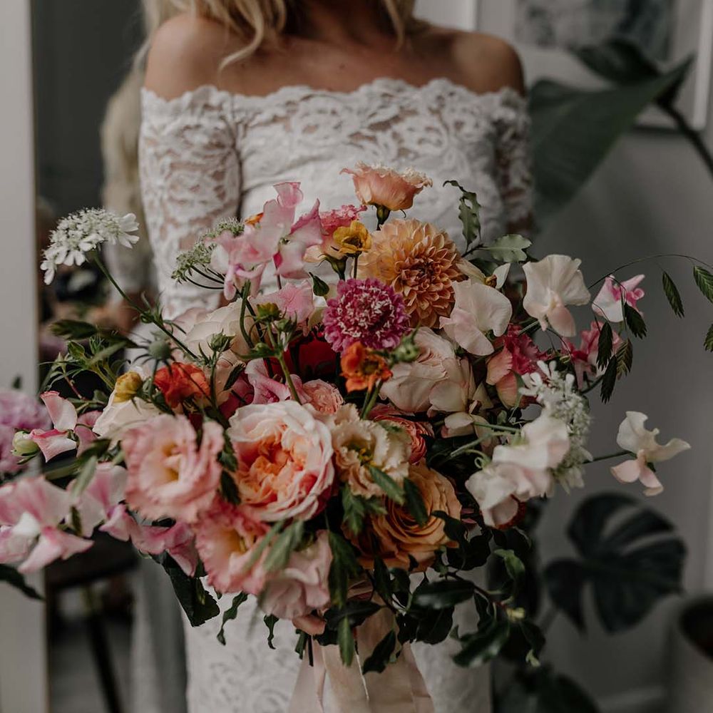 Colourful mixed floral bridal bouquet tied with light pink ribbon