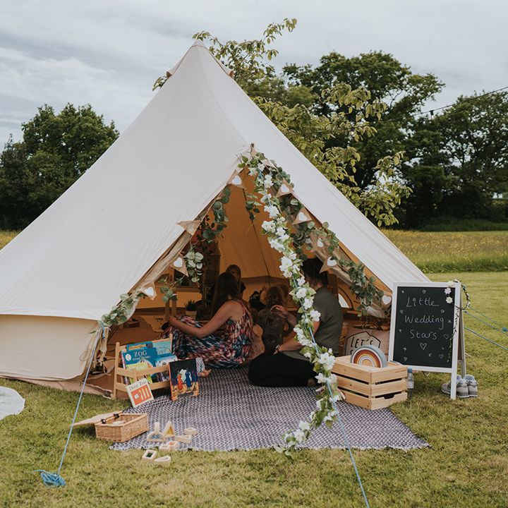 Children's play tent complete with floral decor and wooden chalkboard signage 