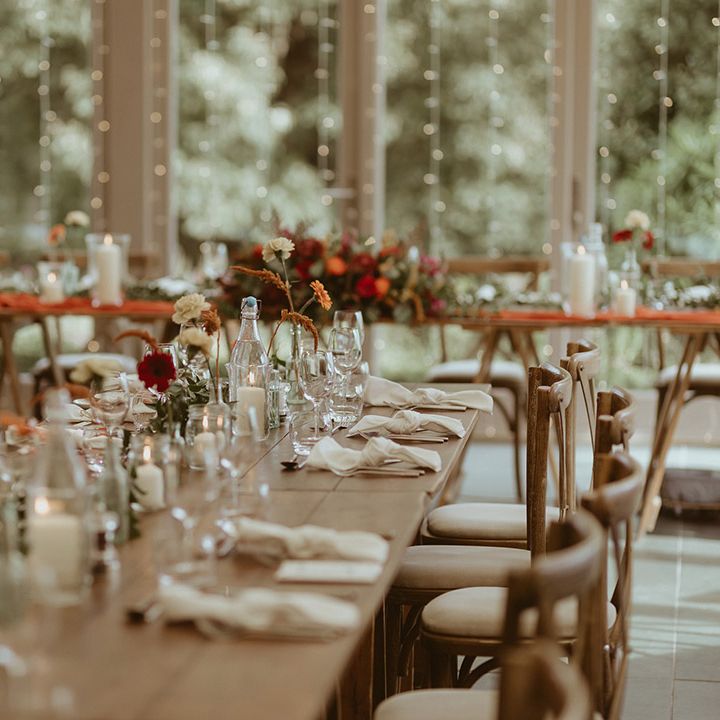 Cosy autumn wedding with fairy lights, candles and warm toned orange wedding flower arrangements at Trevenna Barns in Cornwall 