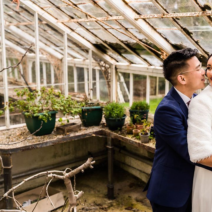 Groom embraces his bride wearing faux fur stole coverup in greenhouse 