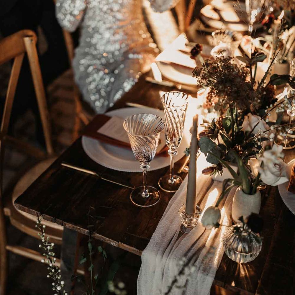 Rustic luxe wedding tablescape with white cloth table runners, foliage, baby's breath, eucalyptus and dried flower floral arrangements, neutral tapered candles and small ceramic vases 