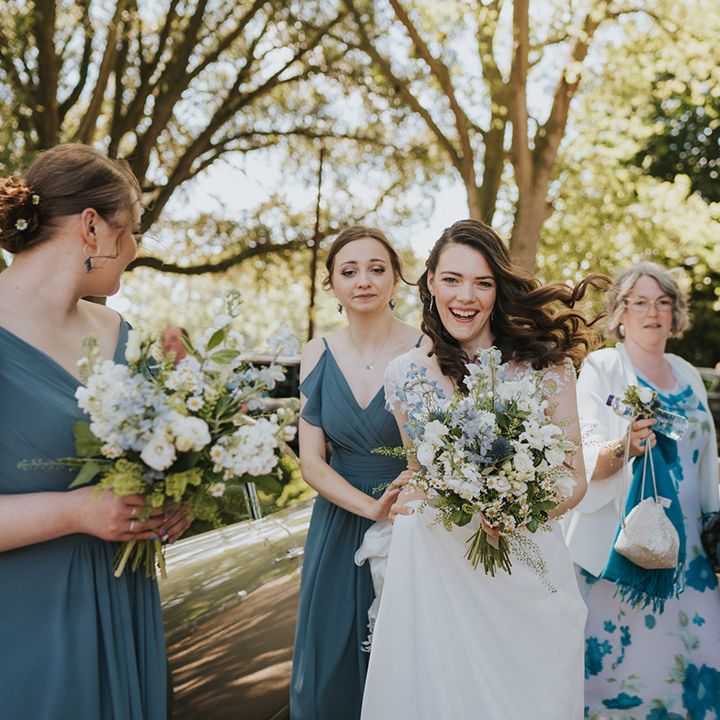 Blue bridesmaid dresses worn by the bridesmaids with a groomsman and wedding guest also wearing blue tones for the rustic wedding 