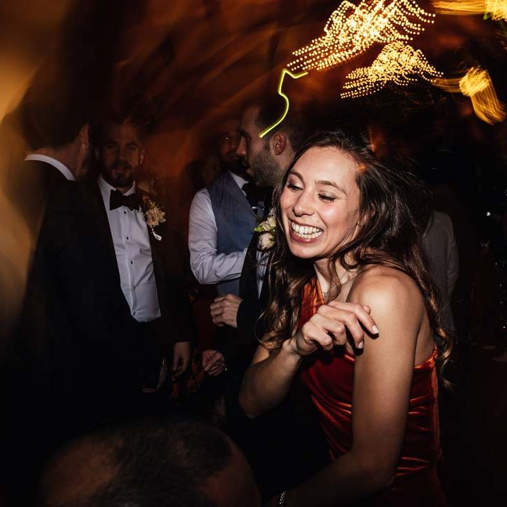 Wedding guest in one shoulder burnt orange bridesmaid dress dancing at wedding party at Brinsop Court wedding venue