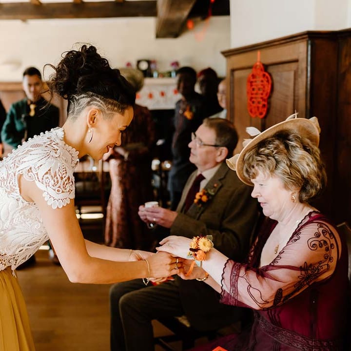 Bride at Broadfield Court in white mesh lace bridal crop top and yellow wedding skirt partaking in Chinese Tea Ceremony 