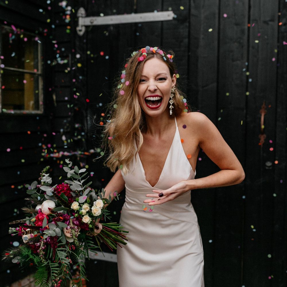 Bride in satin wedding dress covered in confetti at 2020 wedding